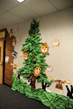 an office cubicle decorated with green paper and animal themed decorations on the wall, along with a christmas tree