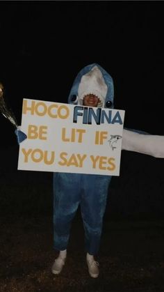 a person in a costume holding a sign that says hoco finna be lit if you say yes