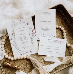 the wedding stationery is laid out on a wicker basket with beads and tassels