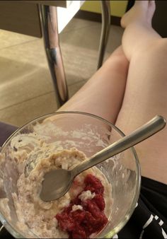 a person sitting on the floor with their legs in a glass bowl filled with food