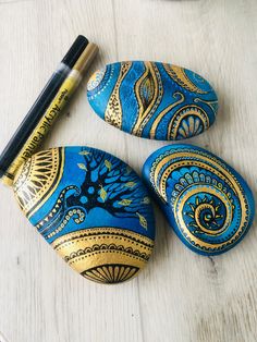 three painted rocks sitting on top of a table next to a pen and marker holder