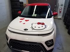 a hello kitty car is parked in a garage with hearts painted on the front hood