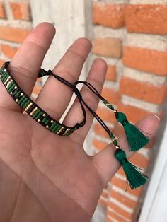 a hand holding a green beaded bracelet with tassels