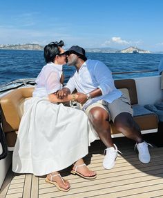 two people sitting on the back of a boat, one kissing the other's cheek