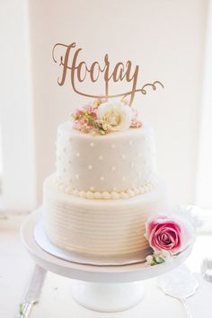 a wedding cake with the word hooray written on top and flowers in front