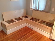 a corner bench made out of plywood is sitting in the middle of a room