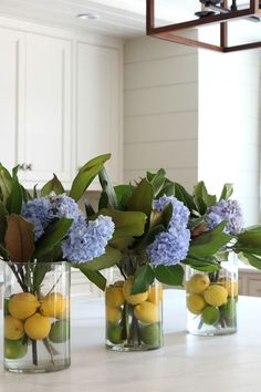 three vases filled with lemons and blue flowers