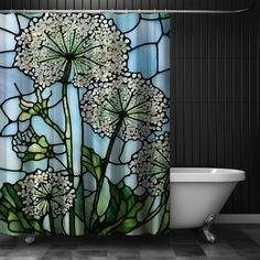 a shower curtain with white flowers and leaves in front of a bathtub that is next to a black wall