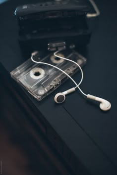 an ipod and headphones are sitting on a black table next to a cassette player