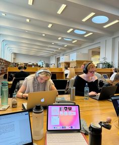 two women sitting at a table with laptops and headphones in front of them