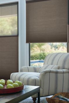 a bowl of apples sitting on top of a table next to a chair and window