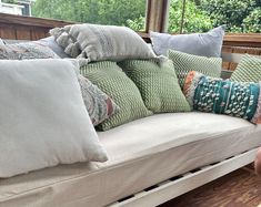 a couch with many pillows on top of it in front of a wooden window sill