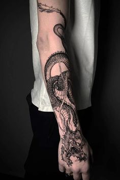 a man's arm with a dragon tattoo on it and a snake in the middle