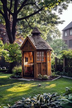 a small wooden shed sitting in the middle of a lush green yard next to a tree