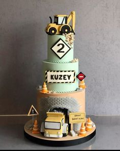 a three tiered cake decorated with construction vehicles and road signs on it's sides