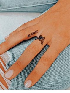 a woman's hand with a small butterfly tattoo on the ring finger that says be good