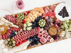 a platter filled with assorted fruits and meats on top of a table