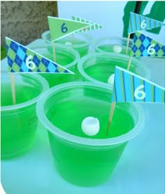 plastic cups filled with green liquid and small flags on top of each cup, sitting on a table