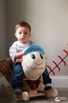 a young boy sitting on top of a stuffed baseball