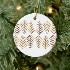 a christmas ornament hanging from a tree with gold foiled leaves on it