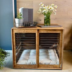 a wooden cabinet with glass doors holding pillows and flowers