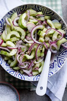 a bowl filled with cucumbers and onions on top of a checkered table cloth