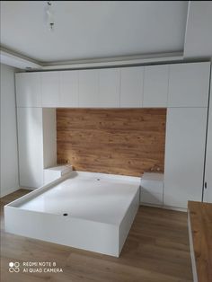 an empty bed in a room with white walls and wood flooring on the side