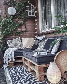 an instagram photo of a couch and pillows on a porch with plants in the background