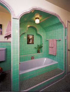 a bathroom with green tile and white fixtures, including a bathtub in the center