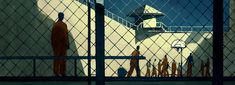 an image of a man behind a fence looking out at the ocean from inside a jail cell