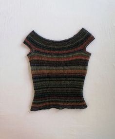 a knitted sweater hanging up on a white wall next to a pair of scissors