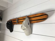 a surfboard mounted to the side of a wall with two hats hanging on it