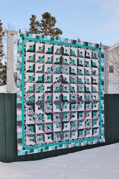 a quilt hanging on a fence in the snow