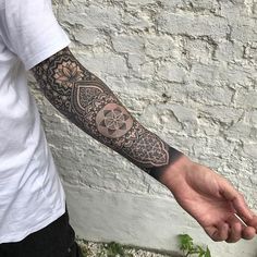 a man with a tattoo on his arm is holding out his hand to the camera