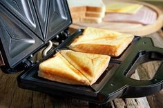 two pieces of toast sitting on top of a black panini maker next to slices of bread