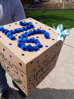 a cardboard box that has been decorated with blue pom poms and the number 25 on it