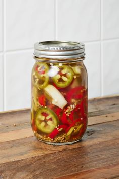 pickled peppers in a mason jar on a wooden table with the words pickled peppers written below