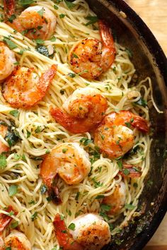 pasta with shrimp and parsley in a skillet on a wooden counter top, ready to be eaten