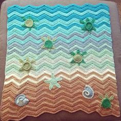 a crocheted blanket with shells and sea turtles on it