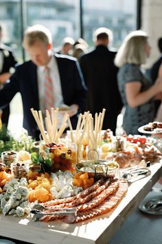 people are standing around a buffet table with many different types of food and drinks on it