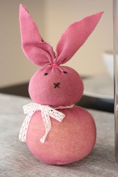 a pink stuffed rabbit sitting on top of a table next to a glass vase and plate