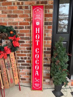 a red sign that says hot cocoa on it next to a christmas wreath and two sleds