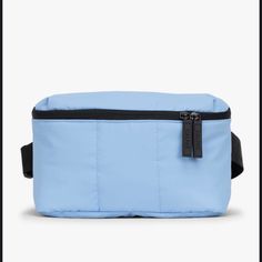 a light blue fanny bag with black zippers on the front and side, sitting against a white background