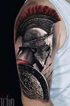 a man's arm with a spartan tattoo on it and his face painted red