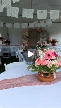 a vase filled with pink flowers sitting on top of a white tablecloth covered field