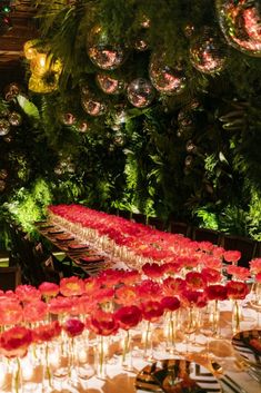 a long table with red flowers on it in front of christmas decorations and baubles