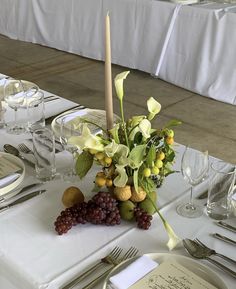 the table is set with white linens, silverware and flowers in a vase