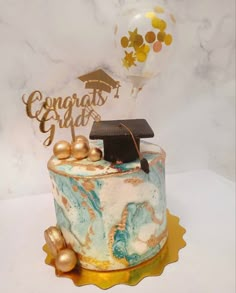 a decorated cake with a graduation cap on top and balloons in the air behind it