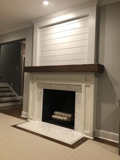 an empty living room with a fireplace and white carpeted flooring in front of it