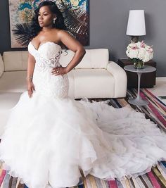 a woman in a white wedding dress standing on a striped rug next to a couch